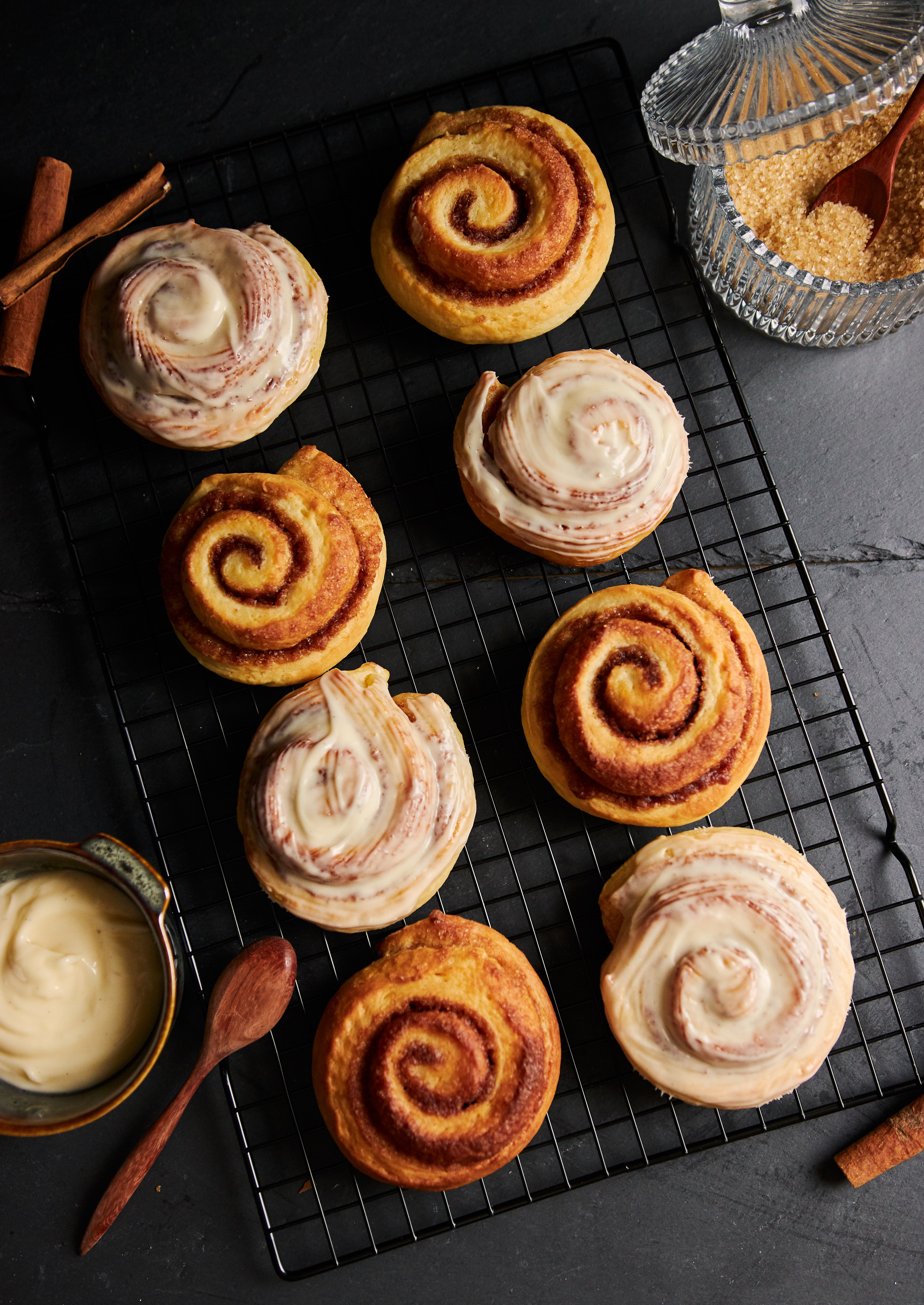 Fresh cinnamon rolls with white glaze on a cooling rack